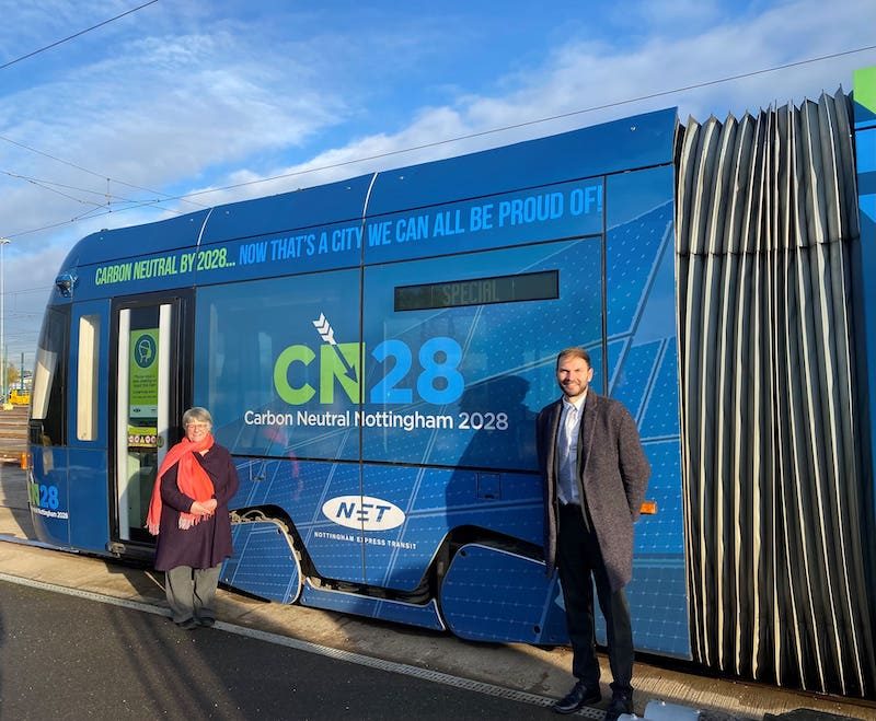 Councillor Sally Longford and Wayne Bexton, director of carbon reduction at Nottingham City Council, pose beside a Nottingham Express Transit tram