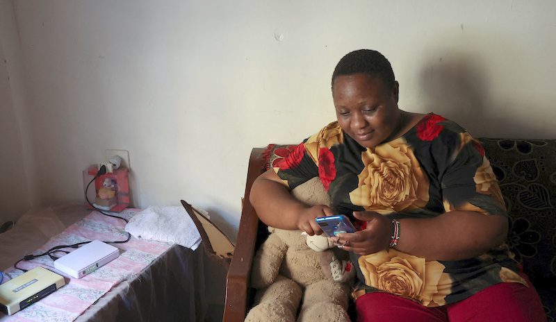 Kenyan migrant worker, Noel Musanga, uses her mobile phone in her apartment in Burj Hammoud, Lebanon