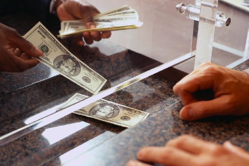 Person, Human, Money Remittance flow between the kingdom of Saudi Arabia and Kenya rose 30.28% in the first eight months of 2023 bank teller handing over dollars at a counter cash