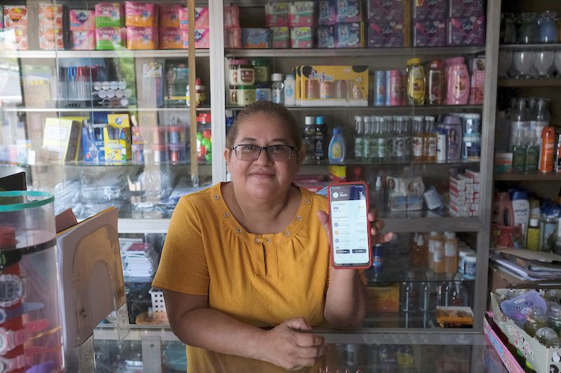 A shopkeeper shows off her bitcoin wallet. The digital currency gained 27 percent in July