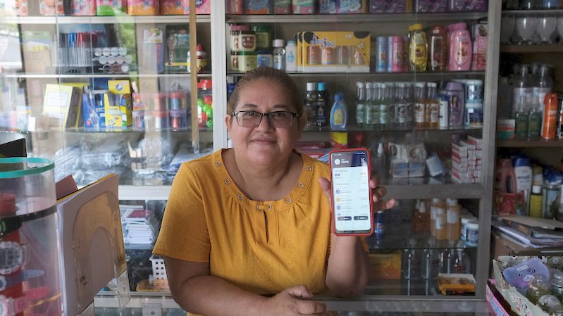 A shopkeeper shows off her bitcoin wallet. The digital currency gained 27 percent in July