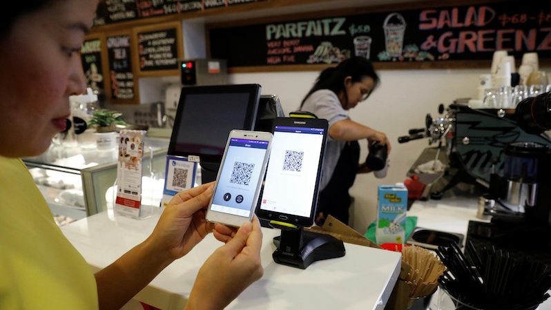A woman pays for her coffee with crypto at a cashless cafe in Singapore
