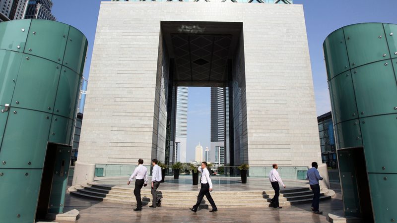 People walk outside the Gate Building at the Dubai International Financial Centre