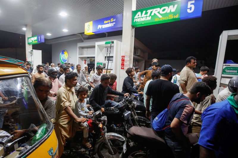 People wait their turn to get fuel at a petrol station, in Karachi, Pakistan