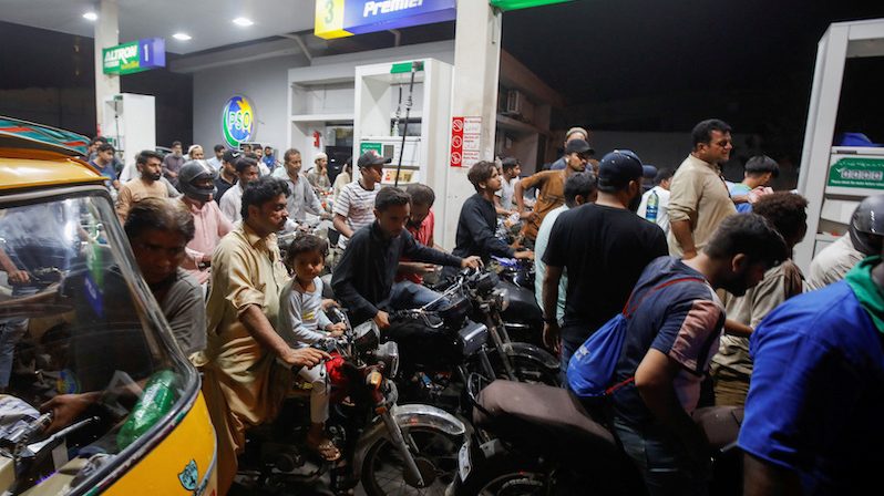 People wait their turn to get fuel at a petrol station, in Karachi, Pakistan