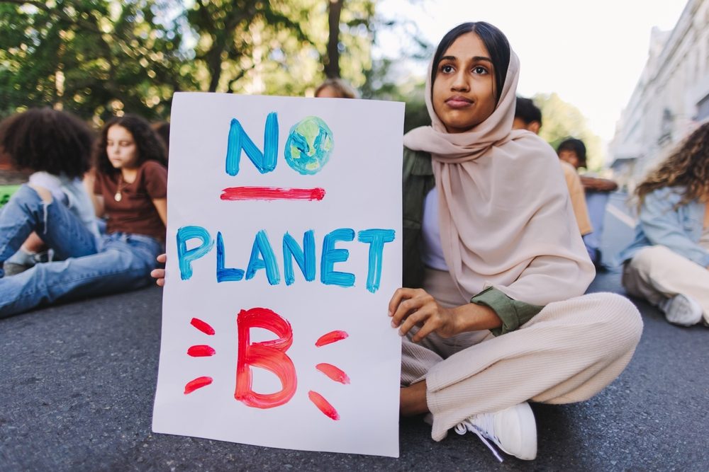 Girl holding a sign calling for sustainability action in the Gulf