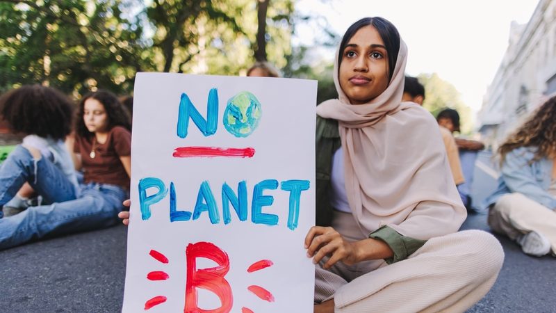 Girl holding a sign calling for sustainability action in the Gulf