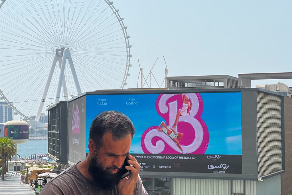 A person walks past a billboard showing an advertisement for the movie "Barbie" on its first day of release in Dubai