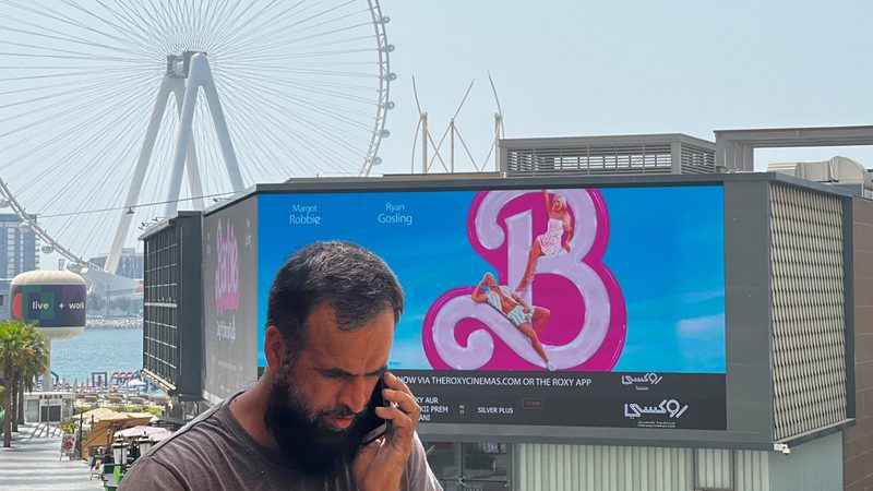 A person walks past a billboard showing an advertisement for the movie "Barbie" on its first day of release in Dubai