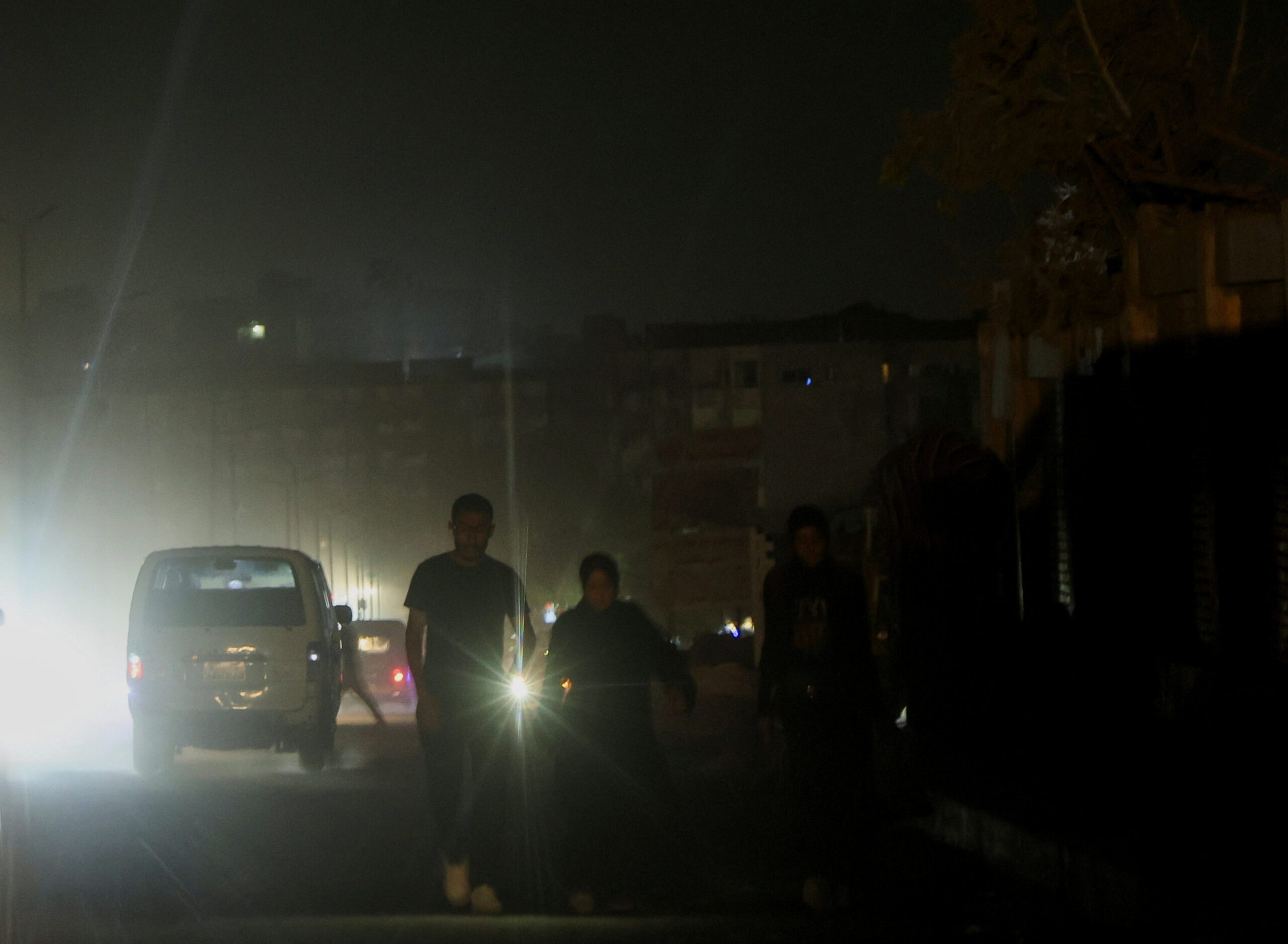 A family use a lantern in the street during a power cut in Cairo, Egypt