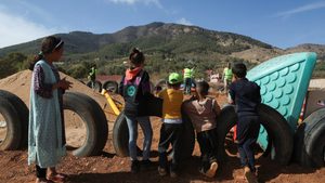Children displaced by the earthquake look on as workers build a playground for them at the Regraga camp