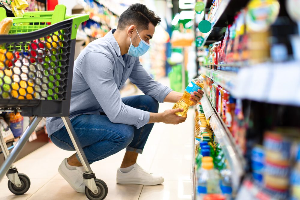 Man in supermarket considering food prices