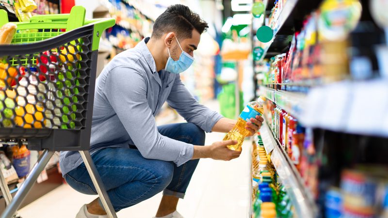 Man in supermarket considering food prices