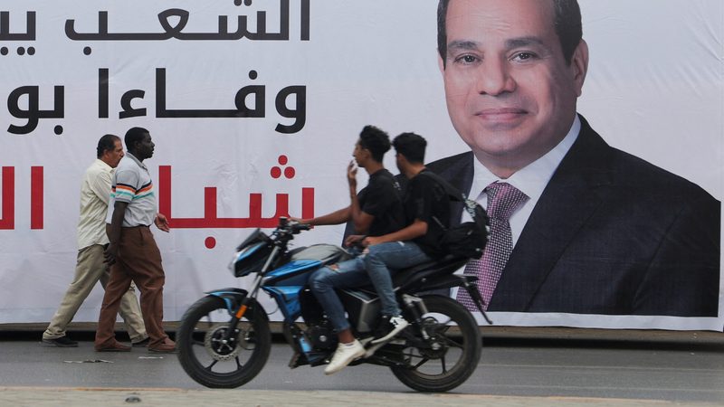People walk past a banner showing President Abdel Fattah Al Sisi in Cairo. Egypt's foreign currency crisis is intensifying as its election nears