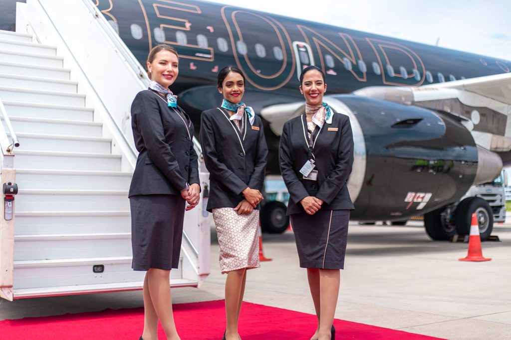 Three female Beond cabin crew stand at the steps of an aircraft luxury leisure airline Beond aims to make the flight an enjoyable element of the leisure experience