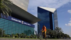 A man rides a bicycle past bank Emirates NBD head office in Dubai, UAE