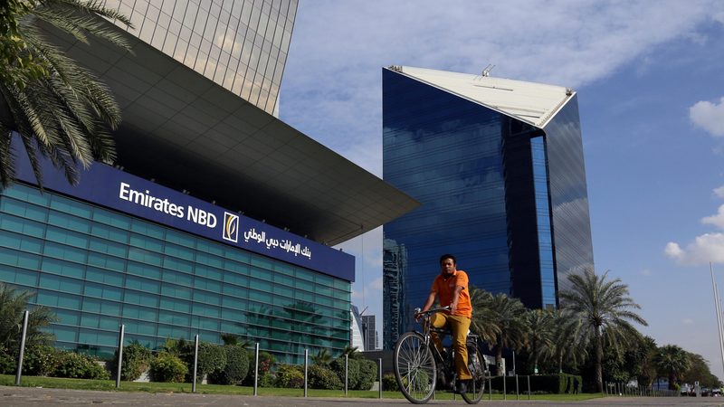A man rides a bicycle past bank Emirates NBD head office in Dubai, UAE