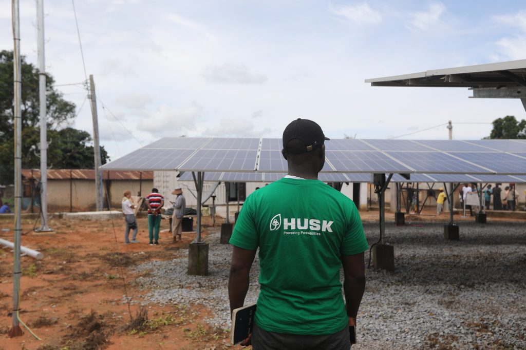 A Husk Power employee stands next to solar panels at the company's minigrid in Kiguna, Nasarawa, Nigeria