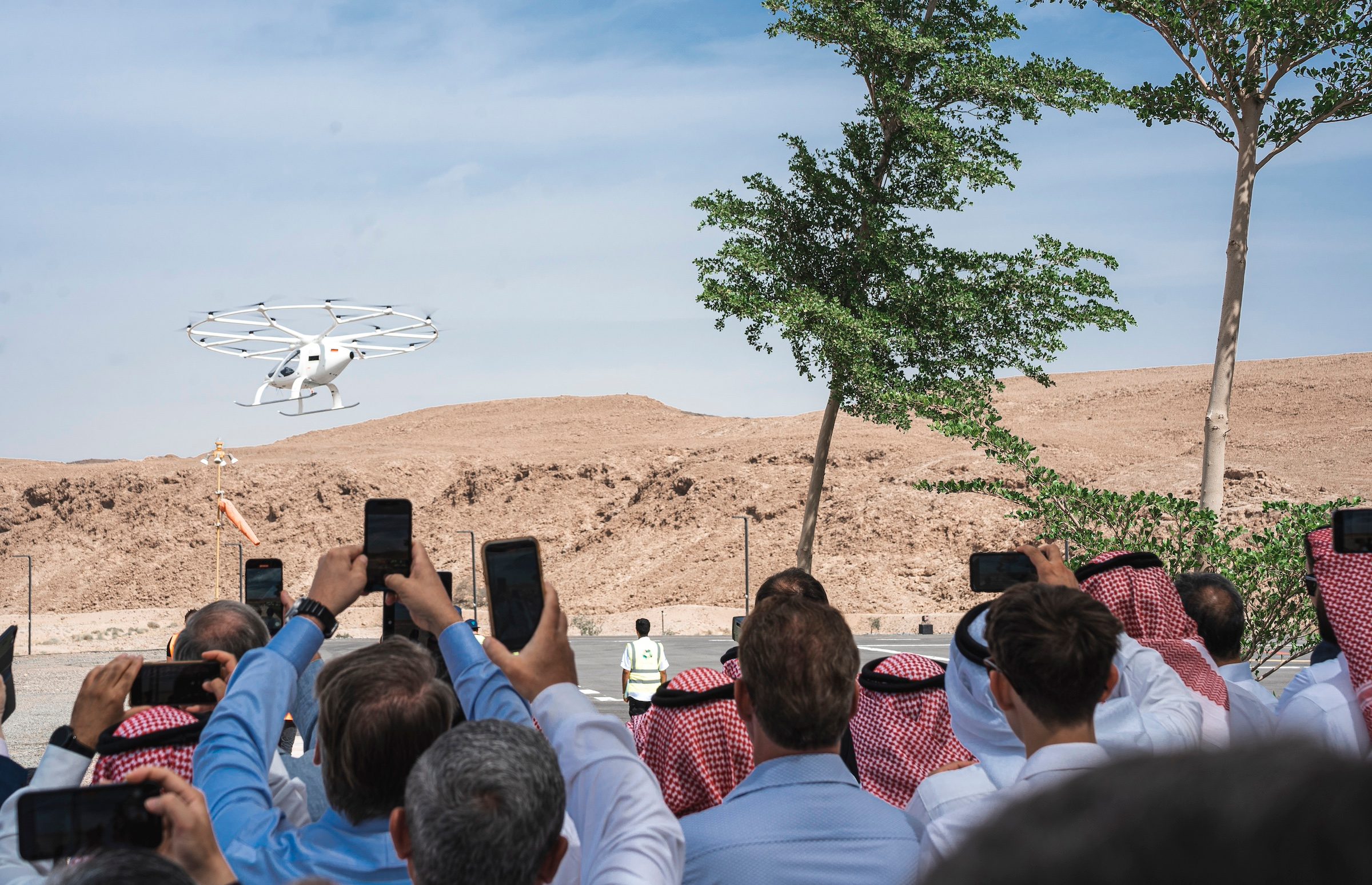 A crowd watches the Neom Volocopter aircraft on a test flight