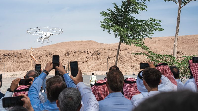 A crowd watches the Neom Volocopter aircraft on a test flight