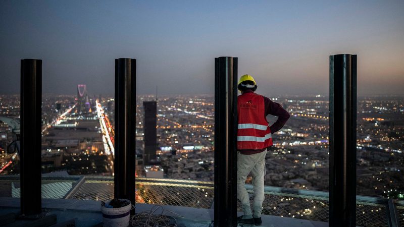 A worker looks out at Riyadh from a tower under construction in the city