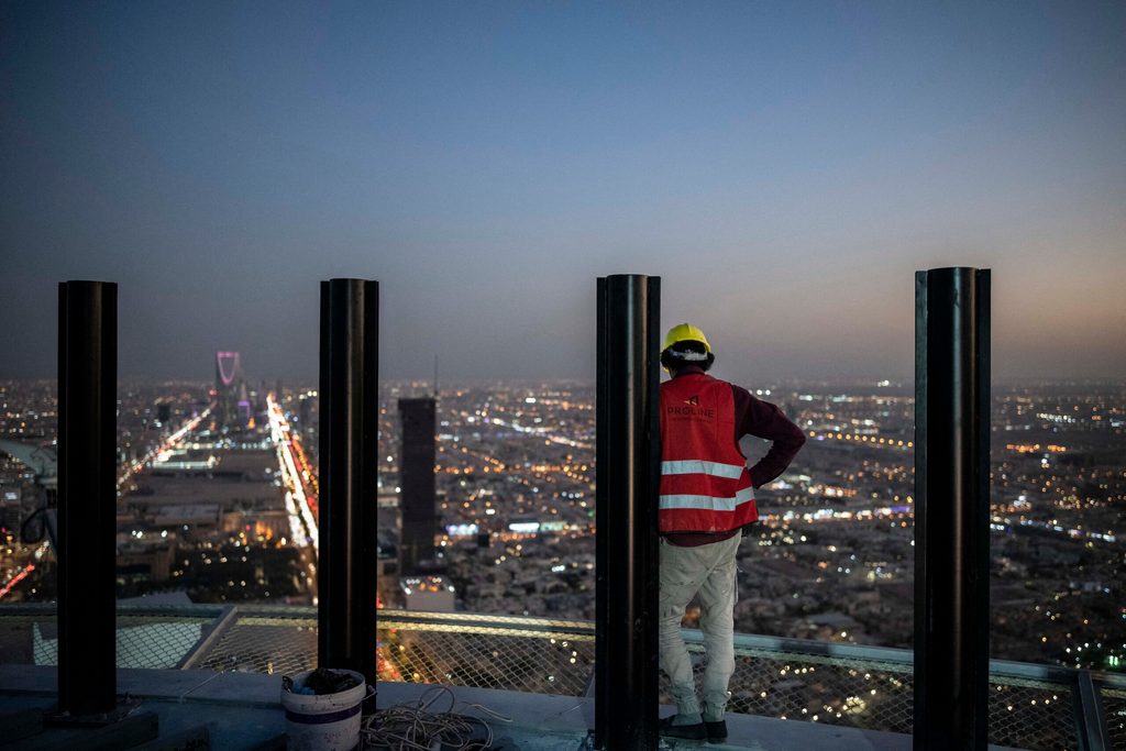 A worker looks out at Riyadh from a tower under construction in the city