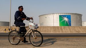 A worker cycles past Aramco oil tanks in Abqaiq, Saudi Arabia