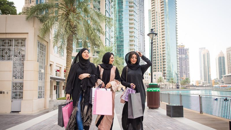 Arabic women with abaya bonding and having fun outdoors - Happy middleastern female friends with traditional muslim dresses meeting and talking while shopping sustainable clothing