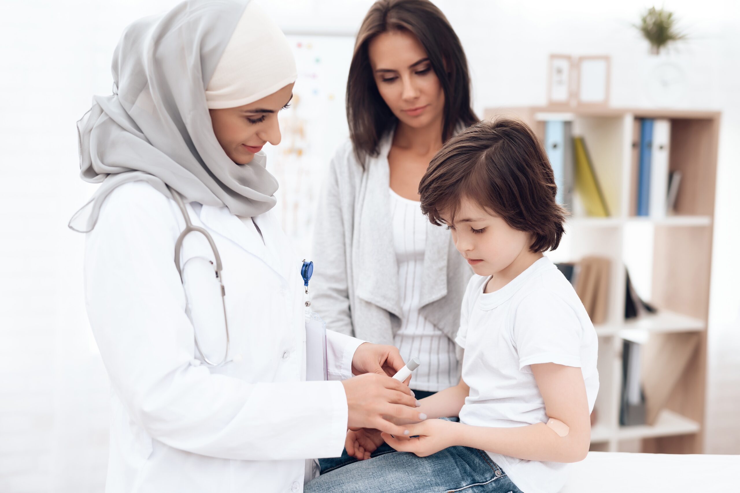 The Arab doctor examines the sick boy. He and his mother came to the hospital. Arabian hospital concept. Pediatrician office and sick child.