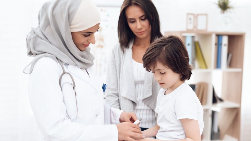 The Arab doctor examines the sick boy. He and his mother came to the hospital. Arabian hospital concept. Pediatrician office and sick child.