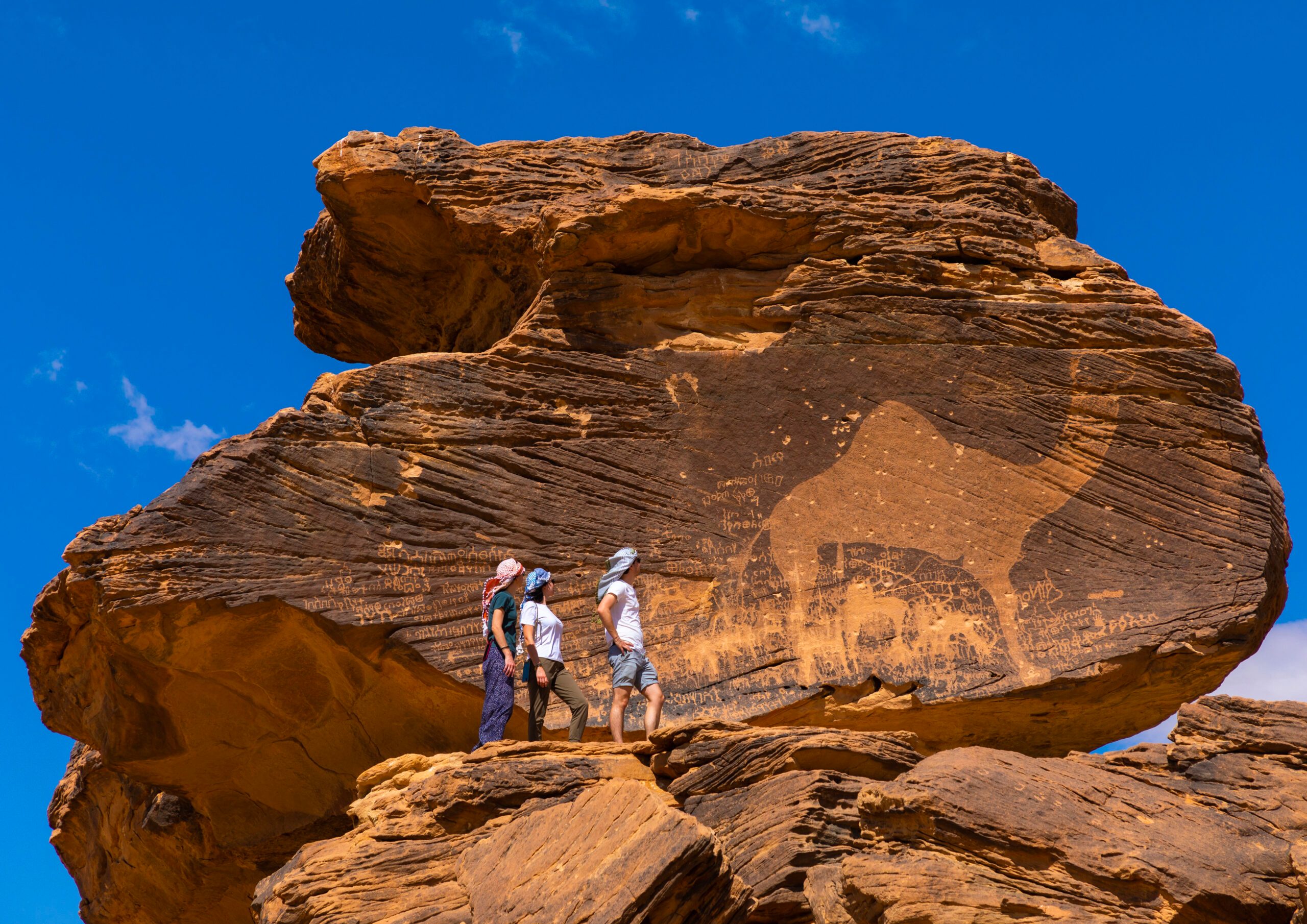 Tourists in front of the Jabal Al-Mawaqi rock art in Saudi Arabia