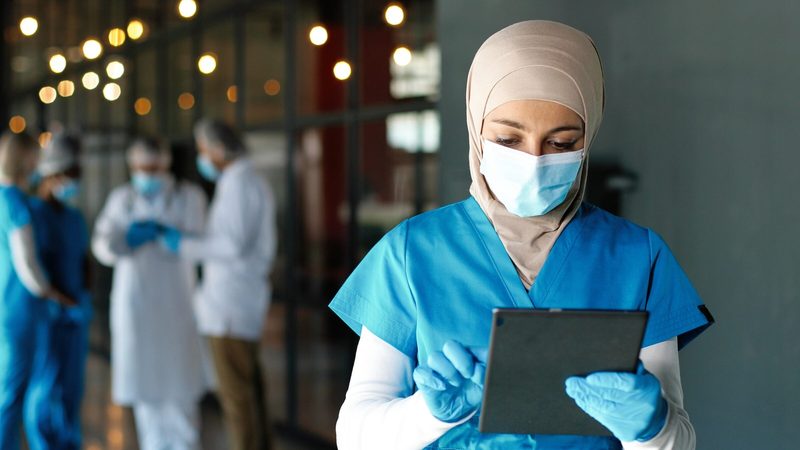 A doctor consults medical records. Aster employs 1,651 doctors and 3,679 nurses