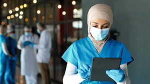 A doctor consults medical records. Aster employs 1,651 doctors and 3,679 nurses