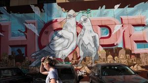 A woman walks past street art in Beirut. About 80% of Lebanon's 5m people now live in poverty