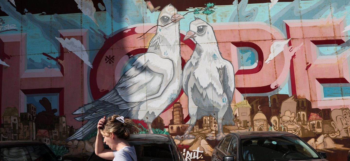 A woman walks past street art in Beirut. About 80% of Lebanon's 5m people now live in poverty