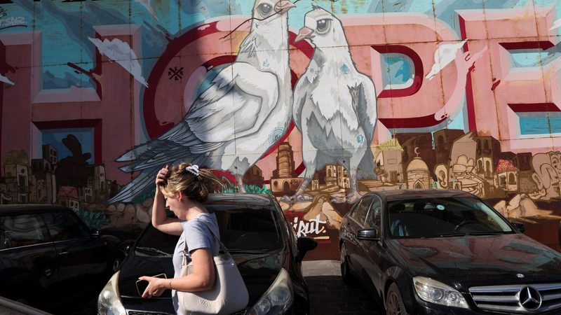 A woman walks past street art in Beirut. About 80% of Lebanon's 5m people now live in poverty