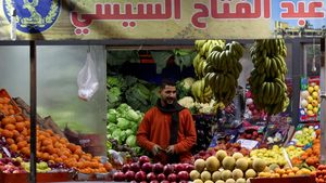 A market worker in Cairo stands under a pro-President Sisi banner. The ADQ deal has raised hopes that Egypt's economy can rebuild