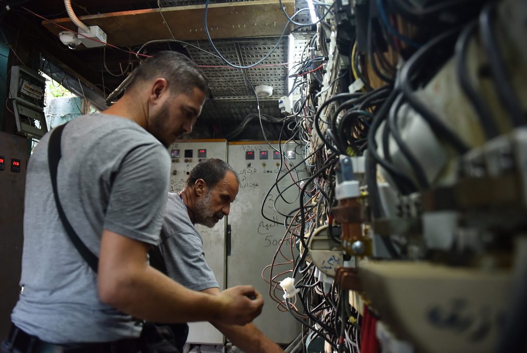 Two men (unrelated to the shooting video) work on an electricity generator in Beirut