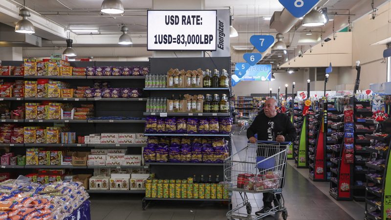 A man pushes a shopping cart near a screen showing the exchange rate of Lebanese pound to U.S. dollars inside a supermarket in Beirut, Lebanon March 9, 2023. REUTERS/Mohamed Azakir