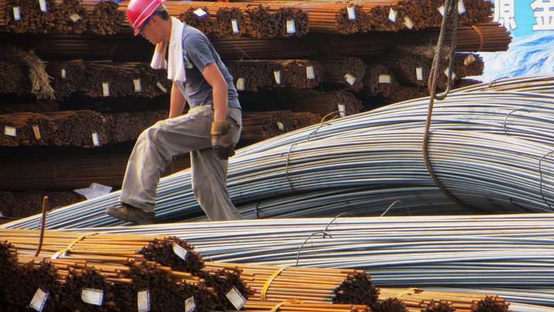 A worker examines rolls of steel rods. Carbon capture can help to reduce emissions from hard-to-abate sectors such as steel production