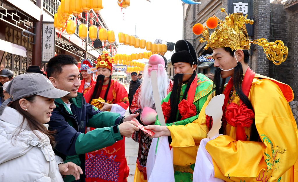 People accept gifts from a man dressed as the Chinese God of Wealth during Spring festival in Zaozhuang, Shandong Province. The region is vital to China's economy