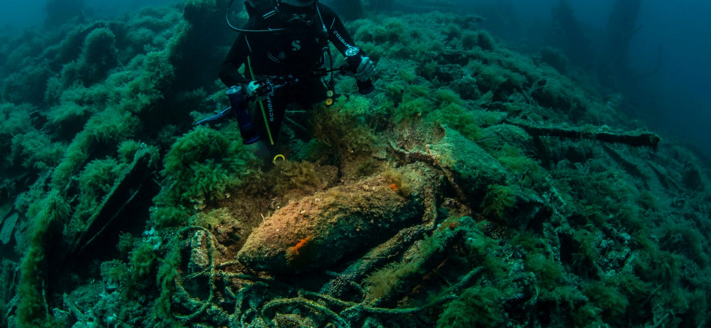 A diver overlooks a heavy shell lying amid the wreck of the British battleship HMS Majestic