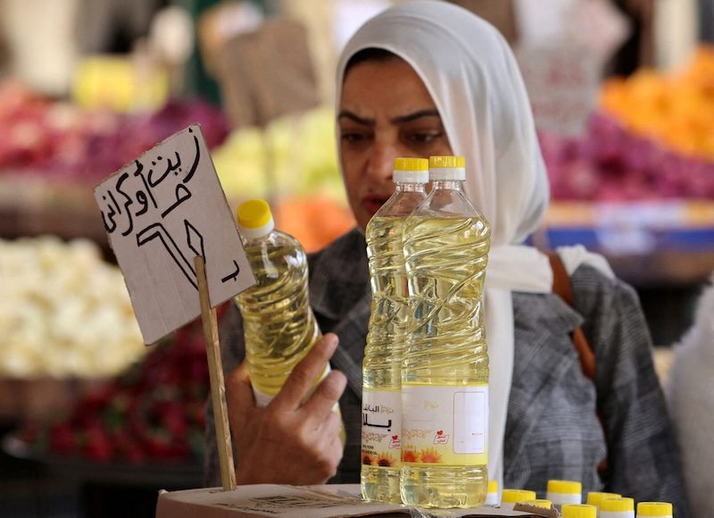 A woman buys cooking oil at a market in downtown Cairo, Egypt