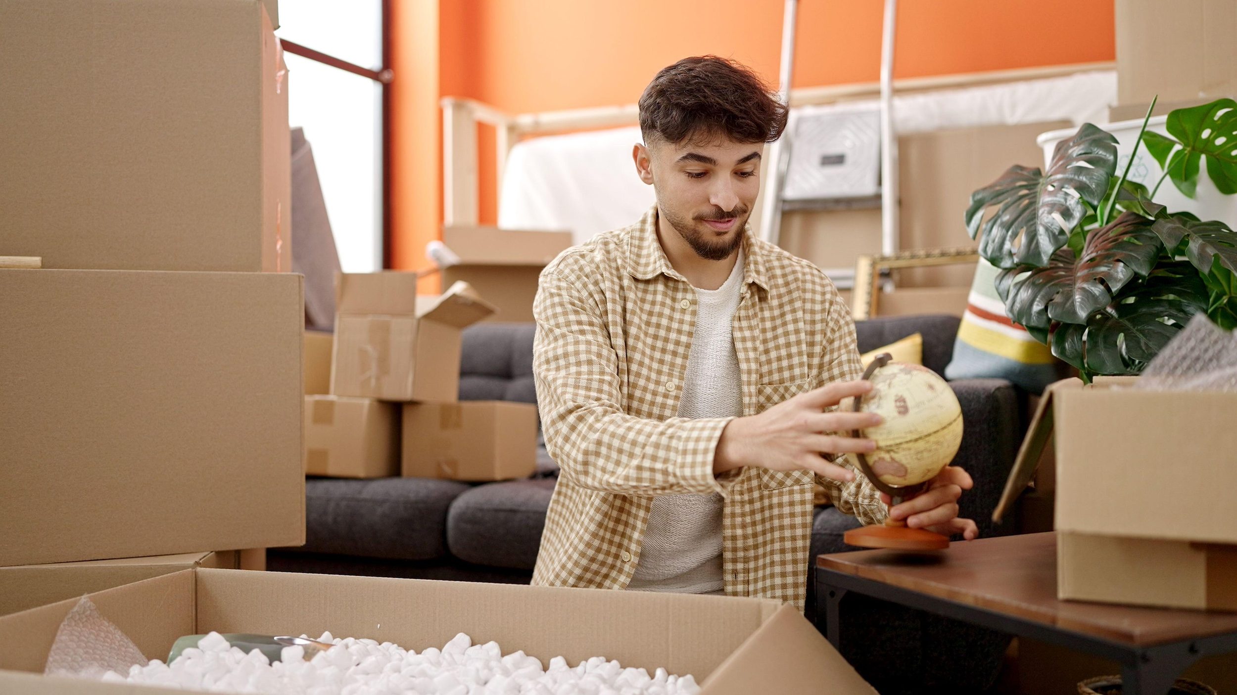 Box, Ball, Baseball 2RD2M3G Young arab man smiling confident unpacking cardboard box at new home globe off-plan developers payment plan Dubai