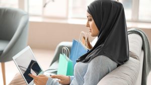 2BF61E1 Young Arab woman using laptop for online shopping at home