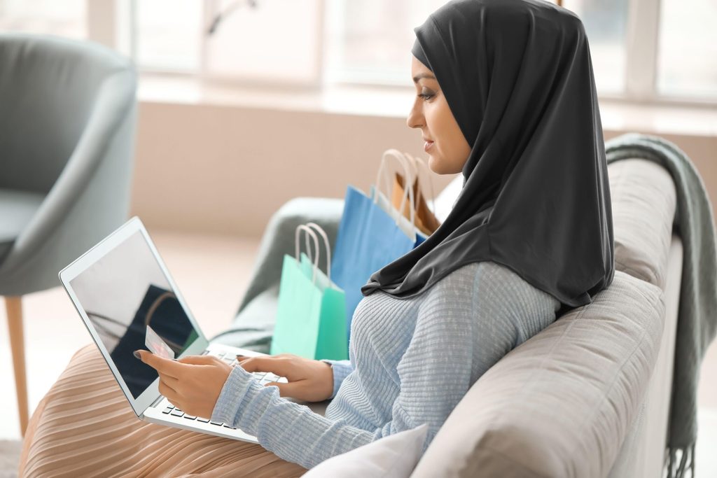 2BF61E1 Young Arab woman using laptop for online shopping at home