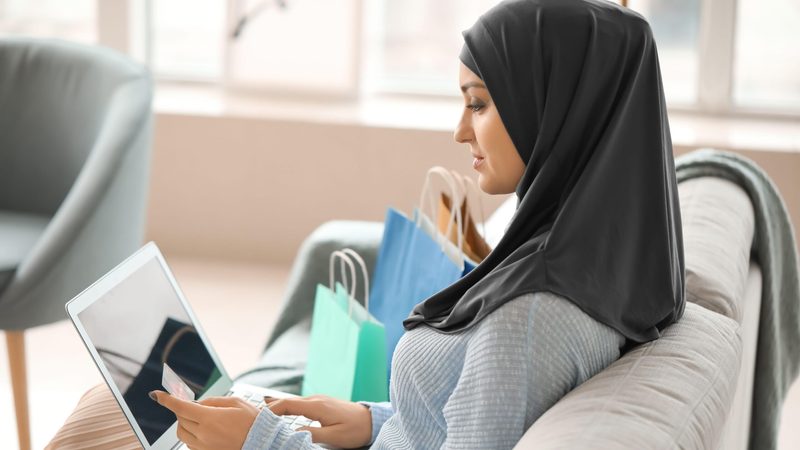 2BF61E1 Young Arab woman using laptop for online shopping at home