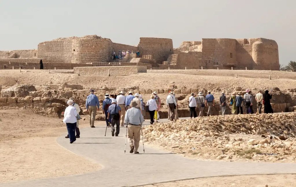 Person, Clothing, Footwear Tourists visiting the Qalat al-Bahrain fort and archaeological site. Tourism revenues increased by almost one third in 2023