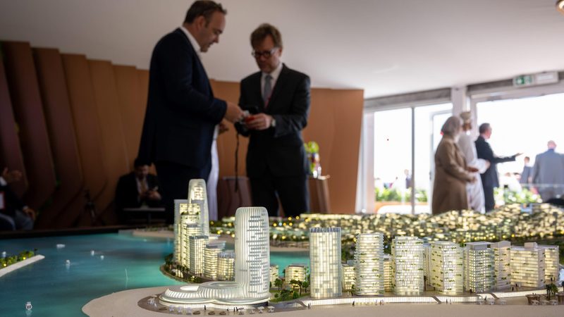 People at a real estate fair in Cannes, France view a model of a proposed development in Oman