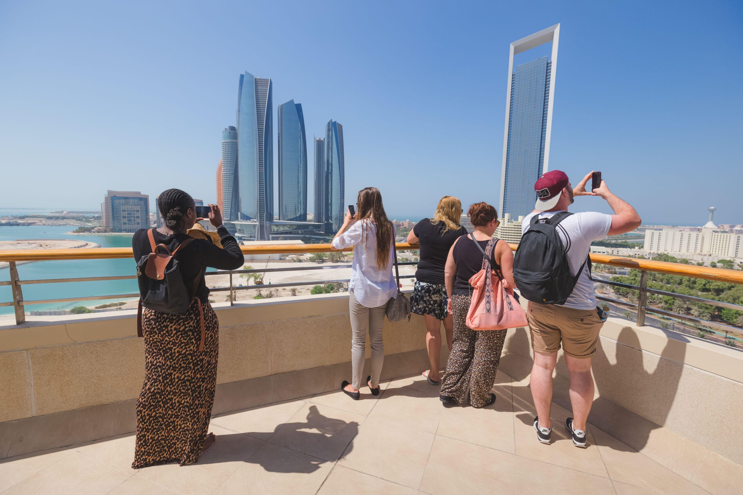 Tourists photograph the Abu Dhabi skyline. Travel funding is small compared to how much tourism contributes to the economy
